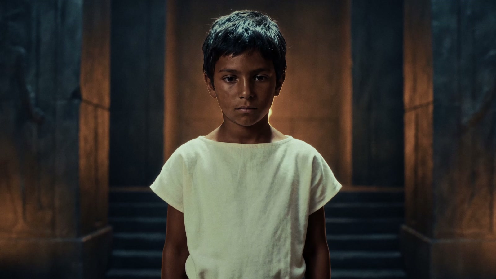 A child stands in a warm, shadowed temple